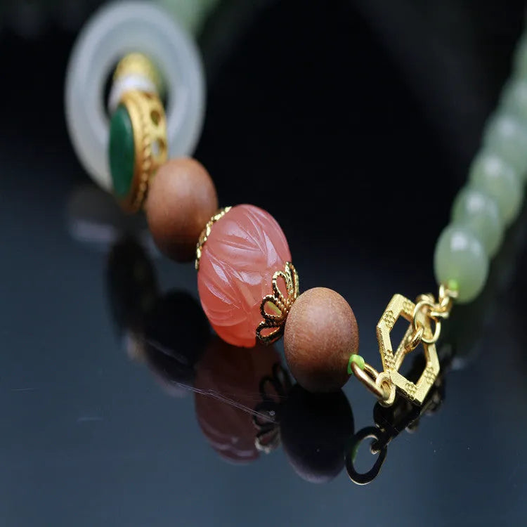 Handmade Hetian jade and white sandalwood necklace with red lotus beads and fu charm, shown with matching bracelet.