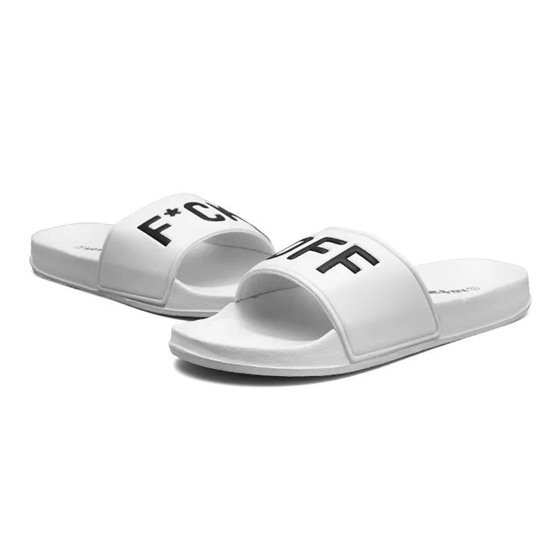 Large black and white open-toe men's slippers with rubber soles, shown on a wooden floor.