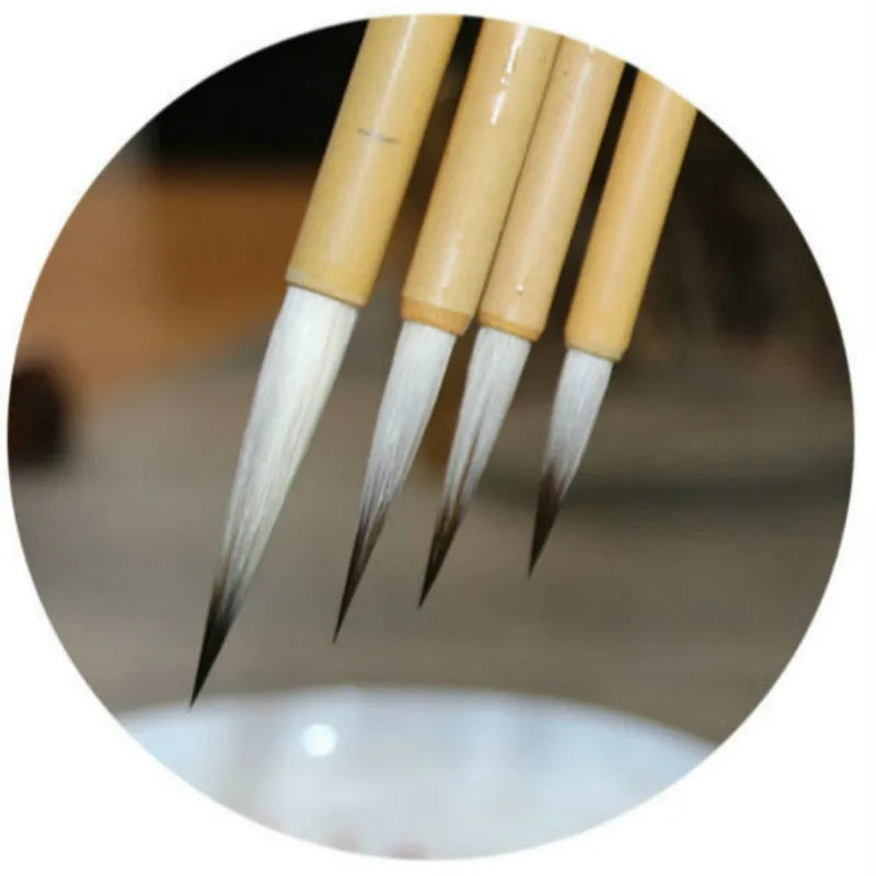 Four Chinese calligraphy brushes with thin gold bodies and natural hair bristles in pine branch colours