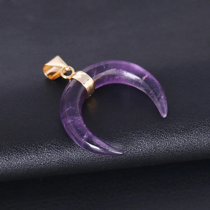 Close-up of a moon-shaped pink natural stone pendant on a metallic chain necklace.