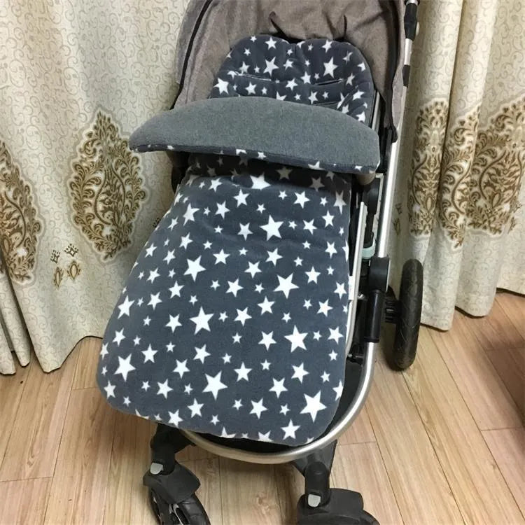 Envelope-style baby stroller sleeping bag in beige colour with thick filling, shown next to a pram.