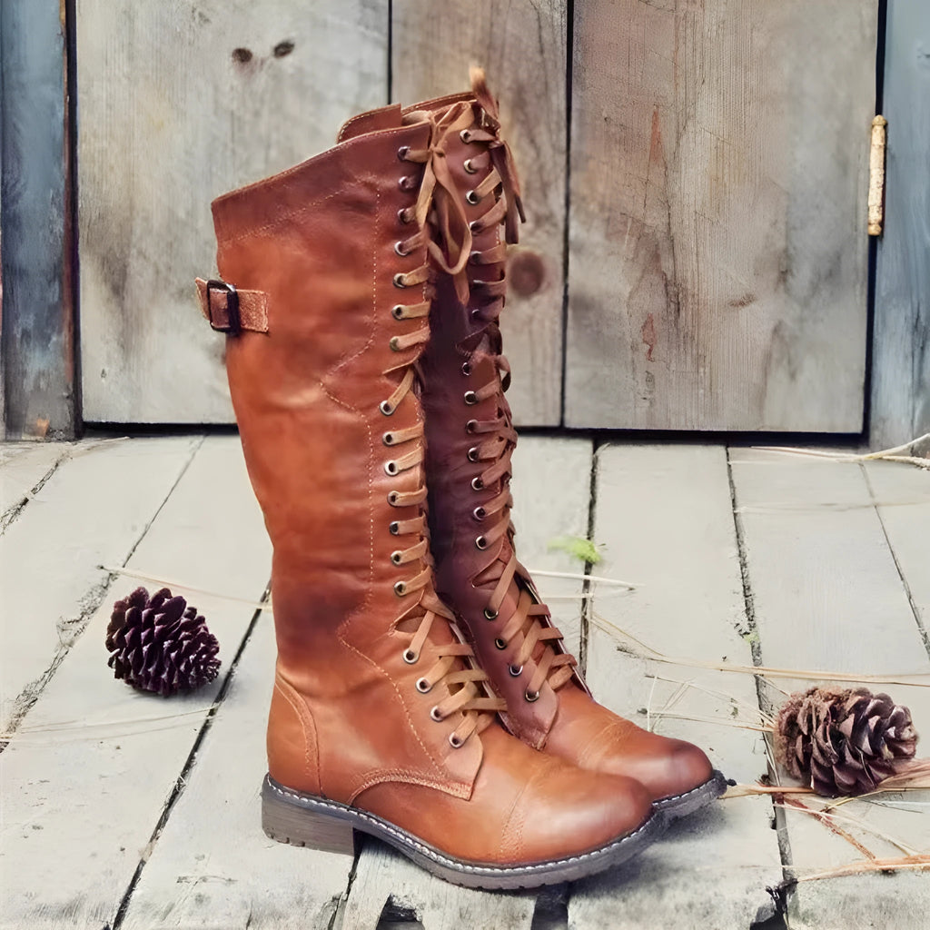 Black chunky heel high leg boots with a round toe and low heel on a plain background.