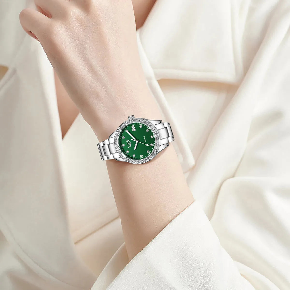Silver stainless steel fashion watch with diamond-encrusted bezel and luminous dial on a wrist.