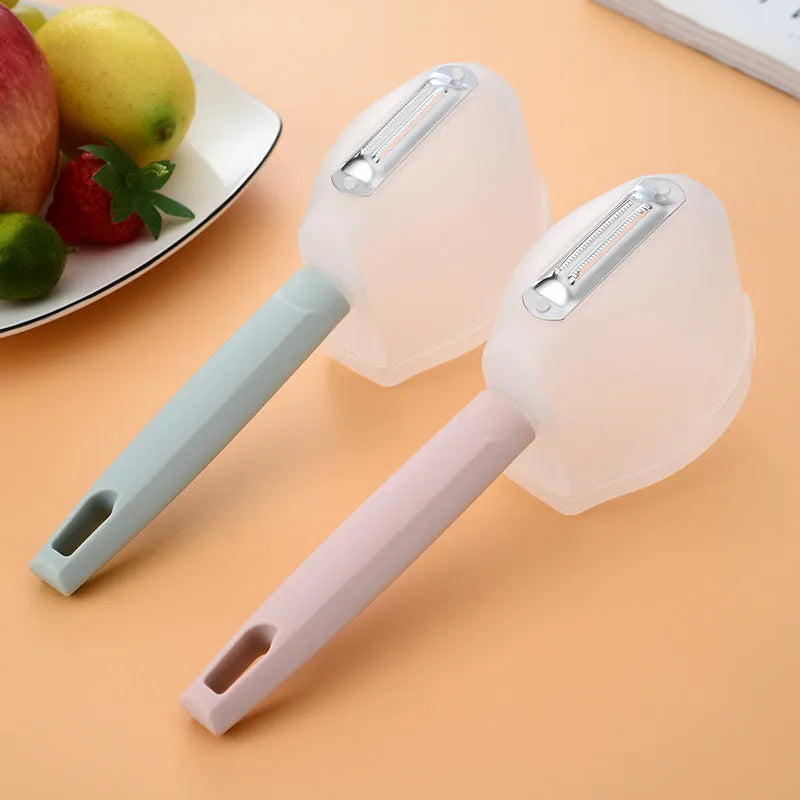 Stainless steel fruit peeler with pink PP plastic handle on a light background