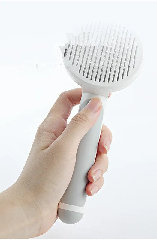 Round handle pet pass-through comb with stainless steel needles and self-cleaning button in pink colour