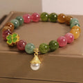 Natural colour tourmaline bracelet with four-leaf clover charm and pearl pendant on wrist