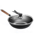 Handmade traditional black cast iron wok with wooden handle on a kitchen counter.