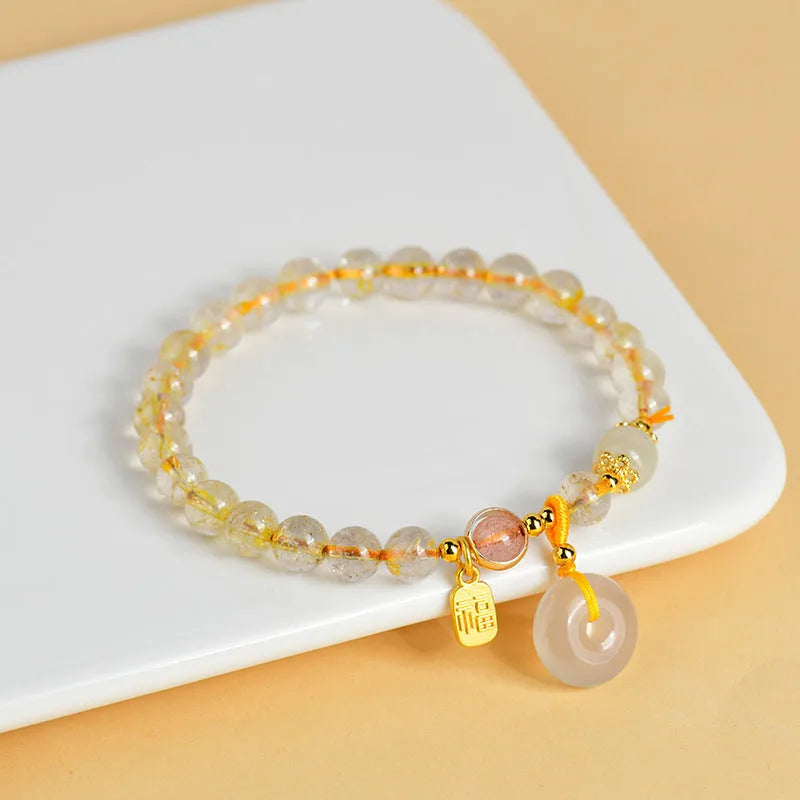 Gold rutilated quartz bracelet with safety buckle and geometric blessing card pendant.