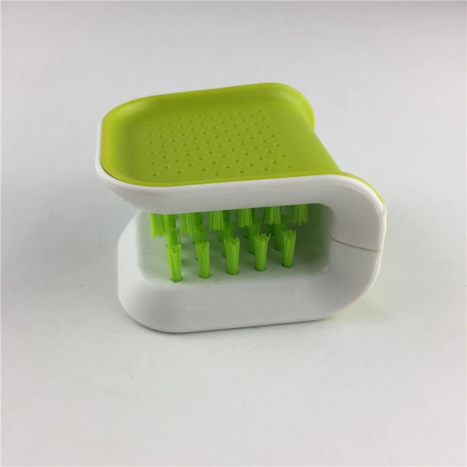 Blue U-shaped plastic brush for cleaning kitchen forks, knives and spoons on a countertop.