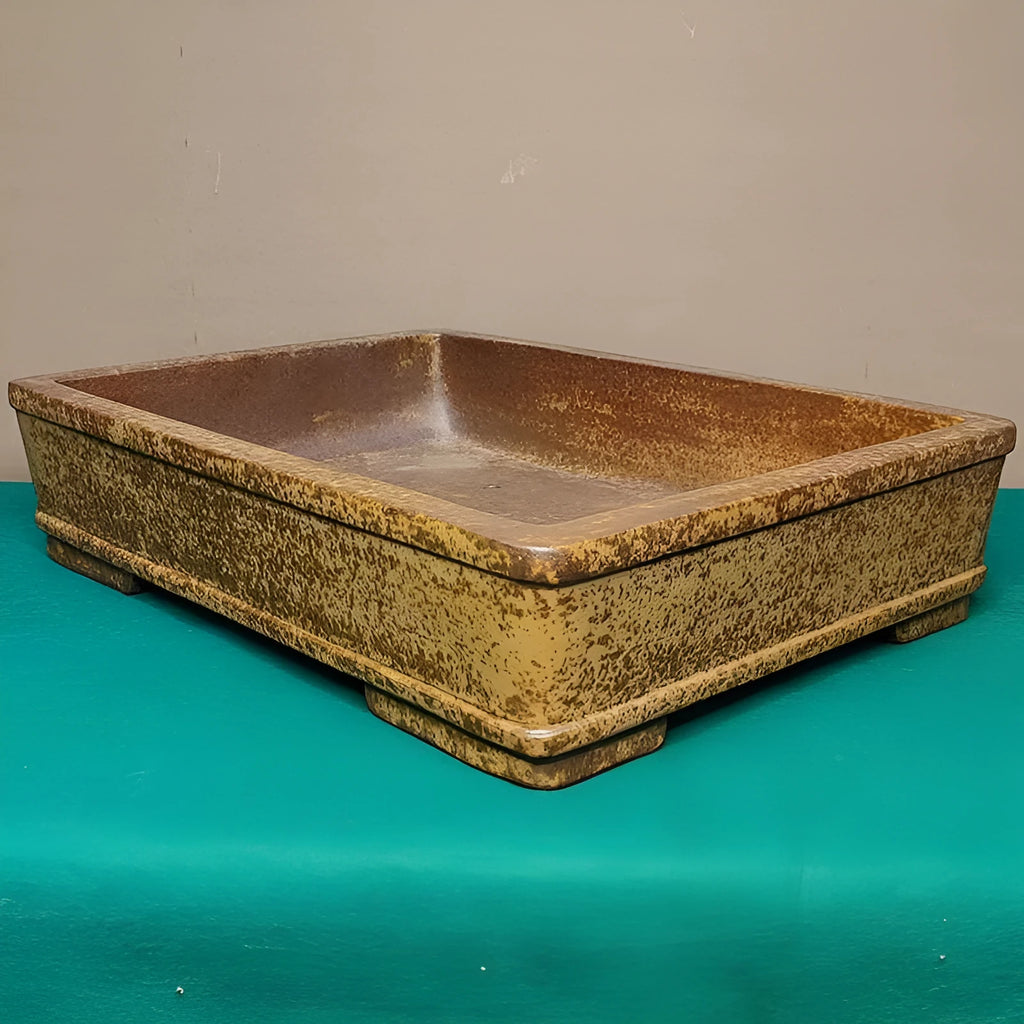 Straight-sided shallow rectangular Yixing flowerpot made from unglazed purple clay on a wooden surface.