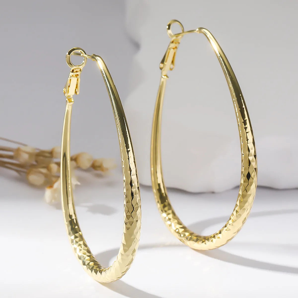 Gold glossy egg-shaped spring fastener earrings made from hypoallergenic copper, unisex geometric design