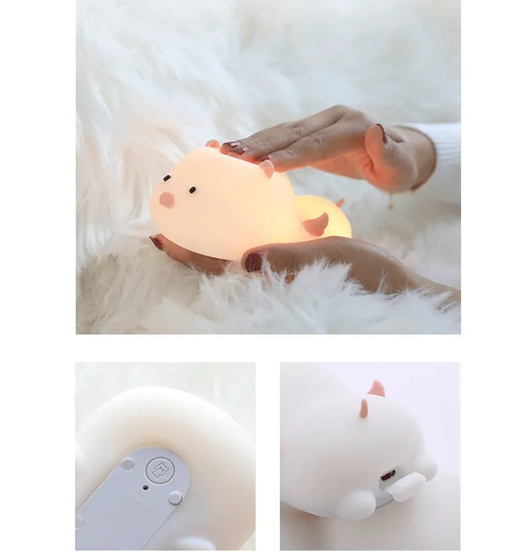Blue rechargeable pig-shaped silicone night light with soft glow on a bedside table.