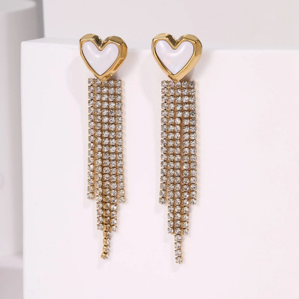 Close-up of a pair of gold plated stainless steel earrings featuring a heart shape design with diamond tassel and geometric star details.