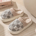 Plaid pattern women's plush indoor slippers in grey with a round toe and flat heel on a non-slip sole.