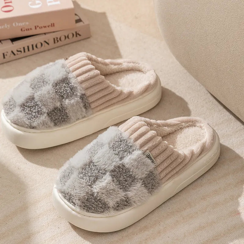 Plaid pattern women's plush indoor slippers in grey with a round toe and flat heel on a non-slip sole.