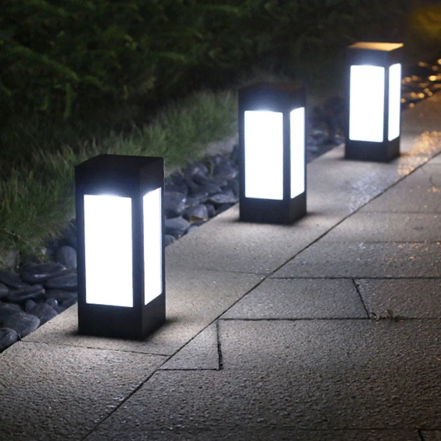 Set of solar-powered garden lights with LED illumination staked along a garden path at dusk