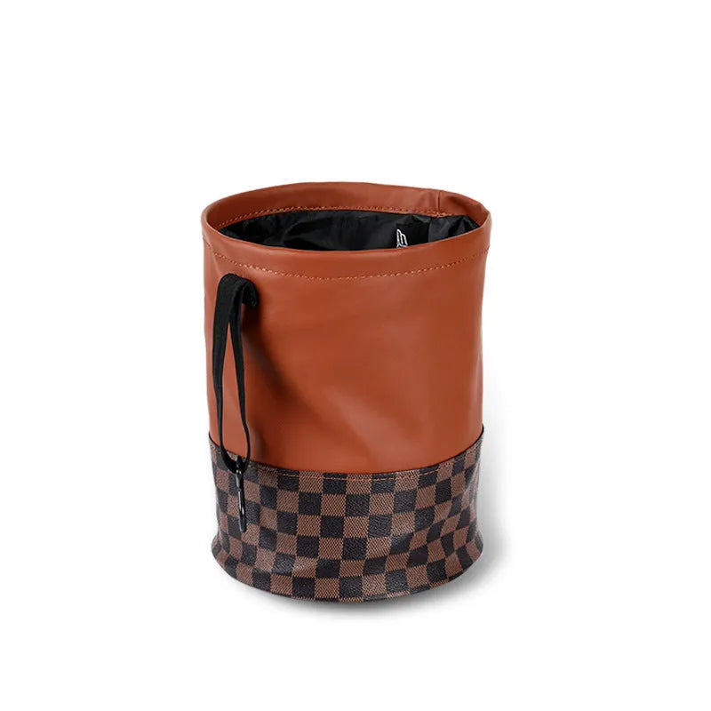 Brown leather retractable car trash can shown in a folded state with a carry handle.