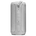 Black outdoor waterproof Bluetooth speaker with control buttons, shown in a garden setting.