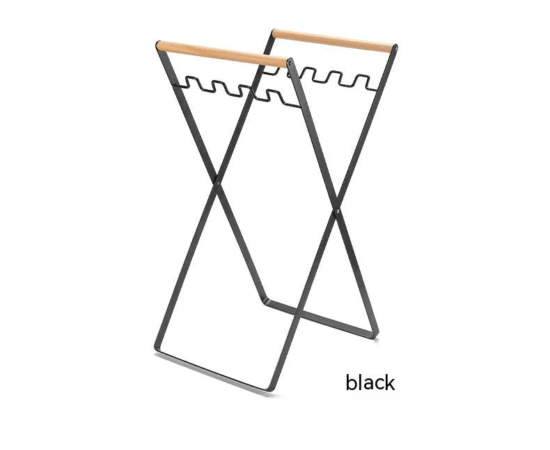 Outdoor black iron folding garbage storage hanger with wooden handle holding a bin bag.