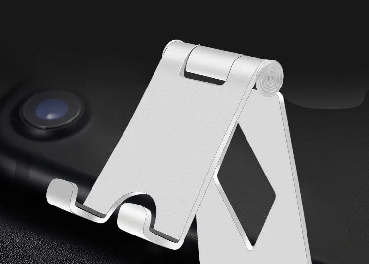 Aluminium alloy mobile desktop stand folding bracket in silver on a desk with a smartphone