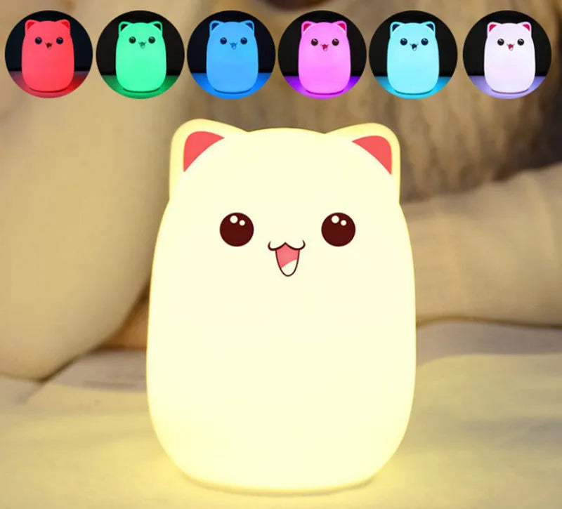 Cartoon silicone clapping night lamp in pink with USB charging cable on a bedside table