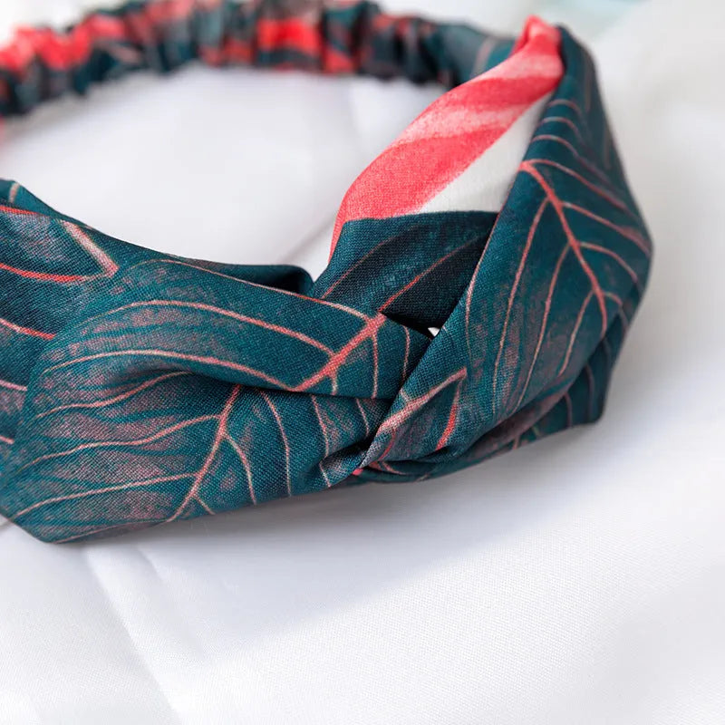 Red cloth headband with banana leaf and cross hair decorative pattern.