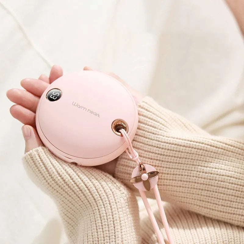 Green hand warmer power bank with digital display showing charge level, next to a charging cable.