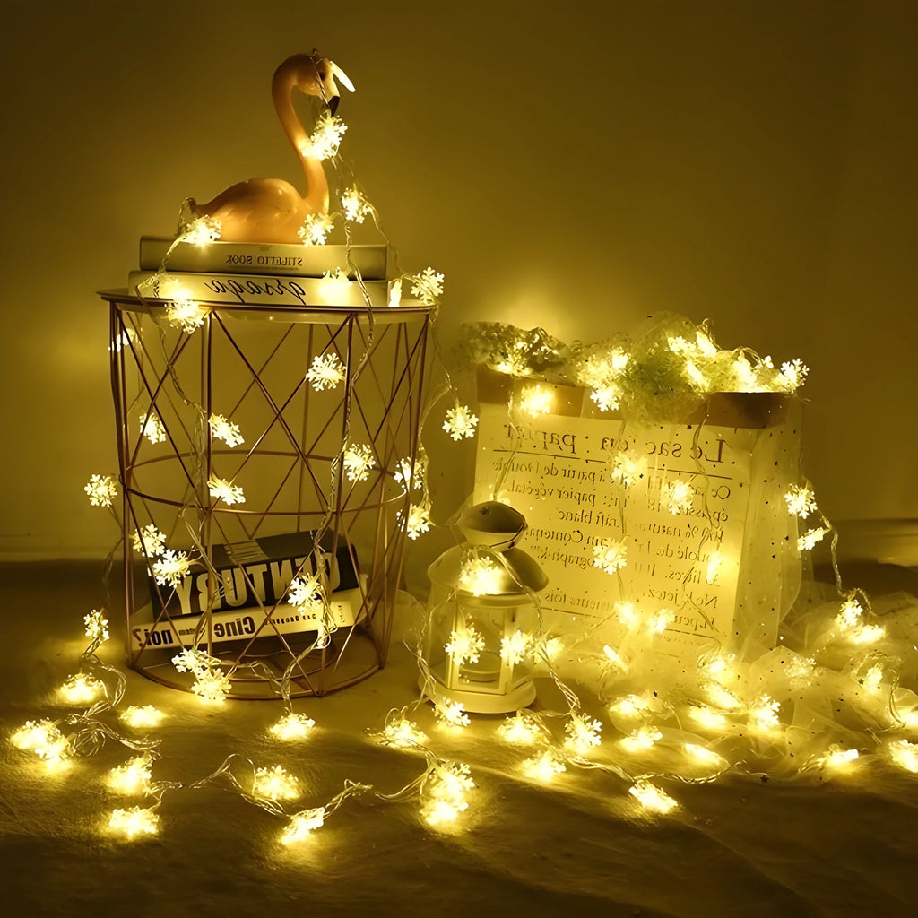 Battery powered LED snowflake string lights in warm white on a garden tree branch for Christmas decoration