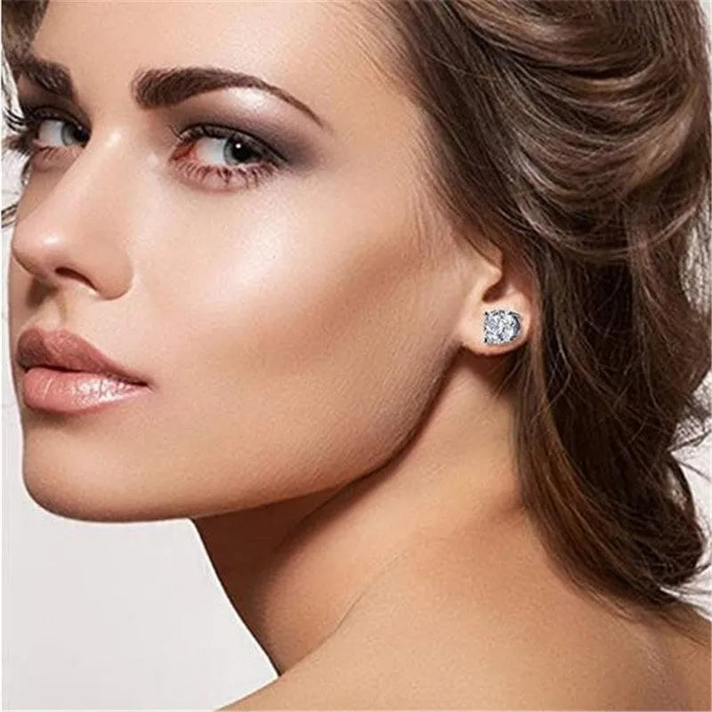 Pair of 925 sterling silver stud earrings with zircon stone detail on a plain background