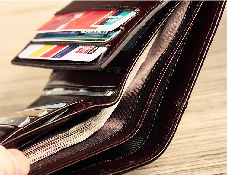 Men's black genuine leather bi-fold wallet open, showing eight card slots, a note compartment, and a zipped coin pouch.