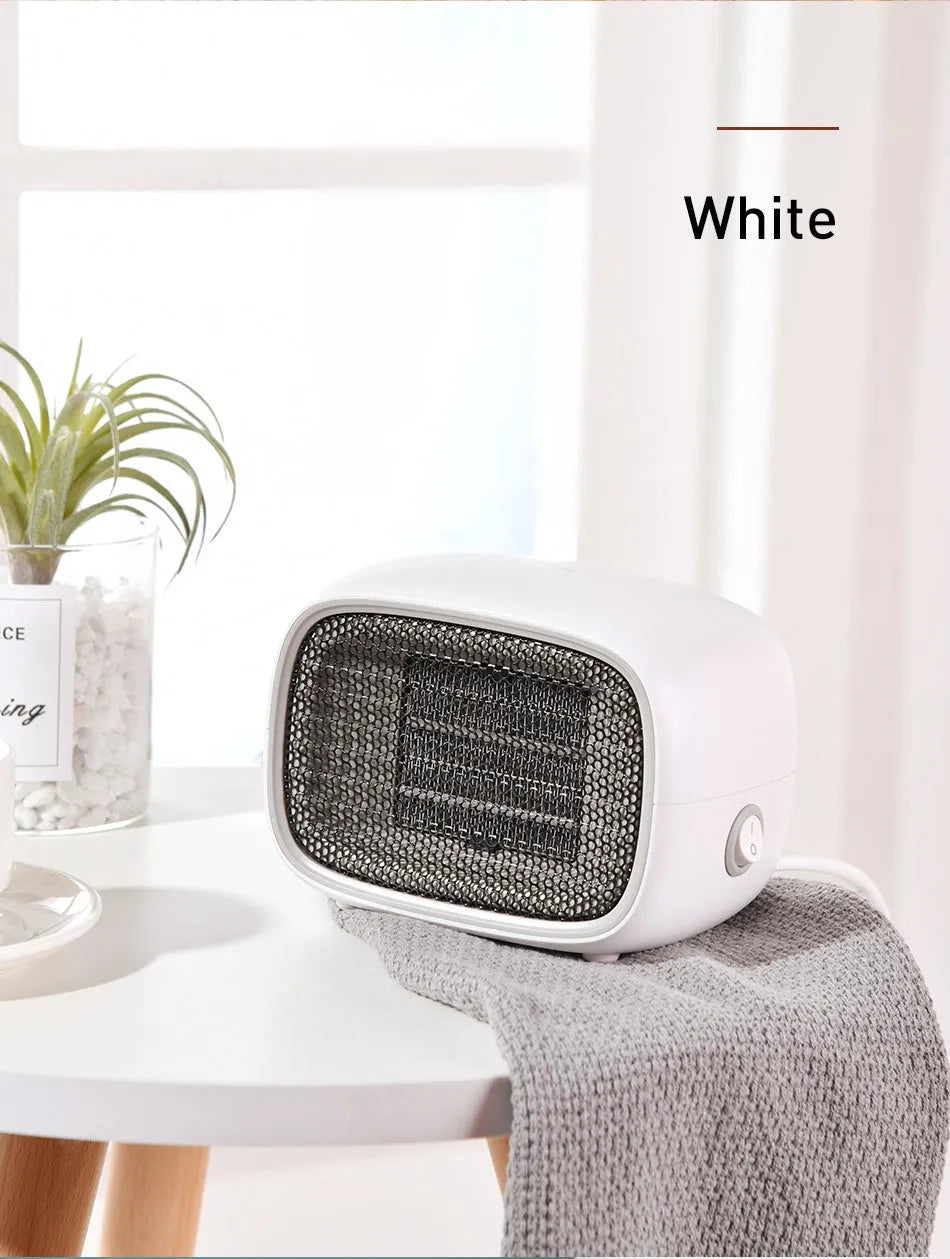 Compact green mini desktop heater with metal grille and EU plug on a wooden desk.