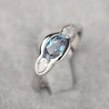 A geometric ellipse-shaped ring with an inlaid zircon, in a white gold colour finish.