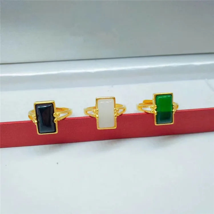 Adjustable brass gold-plated ring with a coloured gemstone inlay on a finger.
