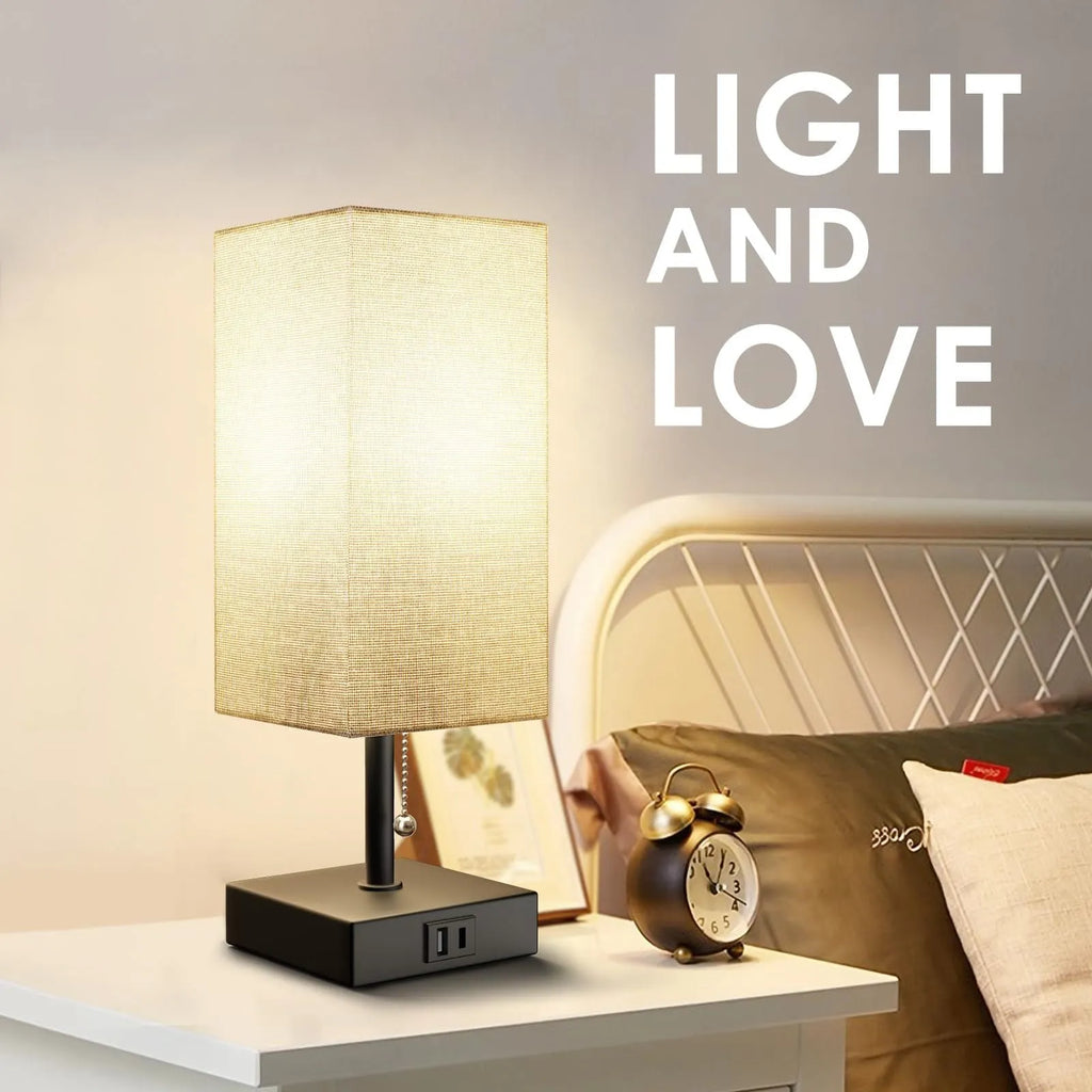 Small bedside table lamp with fabric shade and USB charging ports on a nightstand with pull chain control