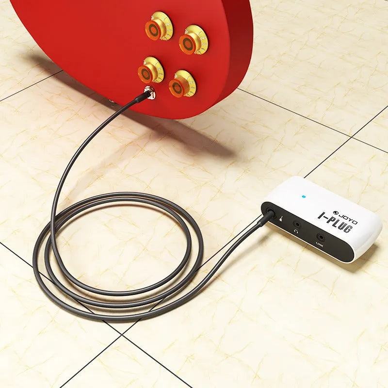 White metal portable headphone amplifier with multi-effects distortion, shown with batteries and connector.