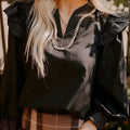Black women's blouse with V-neck collar, long ruffle sleeves, and contrast colour stitching.