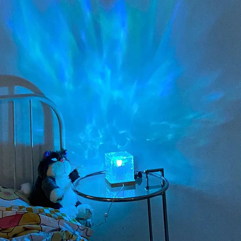LED crystal table lamp projecting blue water ripple light effect on wall.
