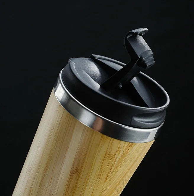 Bamboo coffee cup with double wall insulation, leak-proof lid, and non-slip foam pad on a table