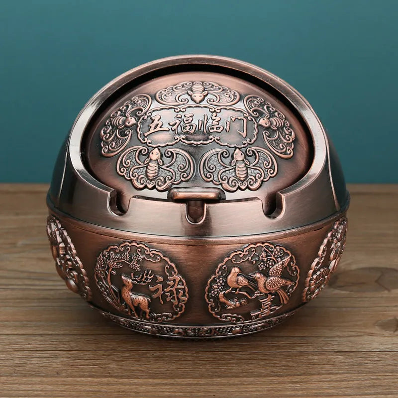 Alloy decorative ashtray in bronze with ornate peacock motif and cigarette extinguishing slot.