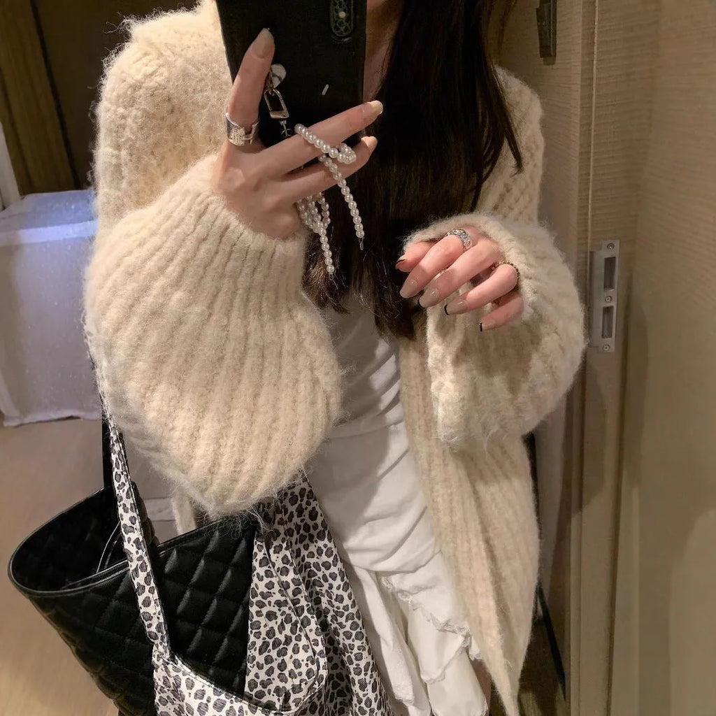 A woman wearing a thick, dark grey hooded cardigan with a loose, longline fit.