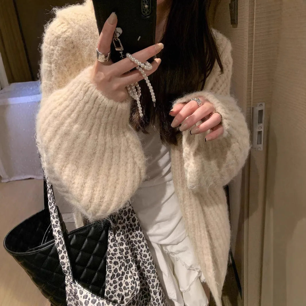 A woman wearing a thick, dark grey hooded cardigan with a loose, longline fit.