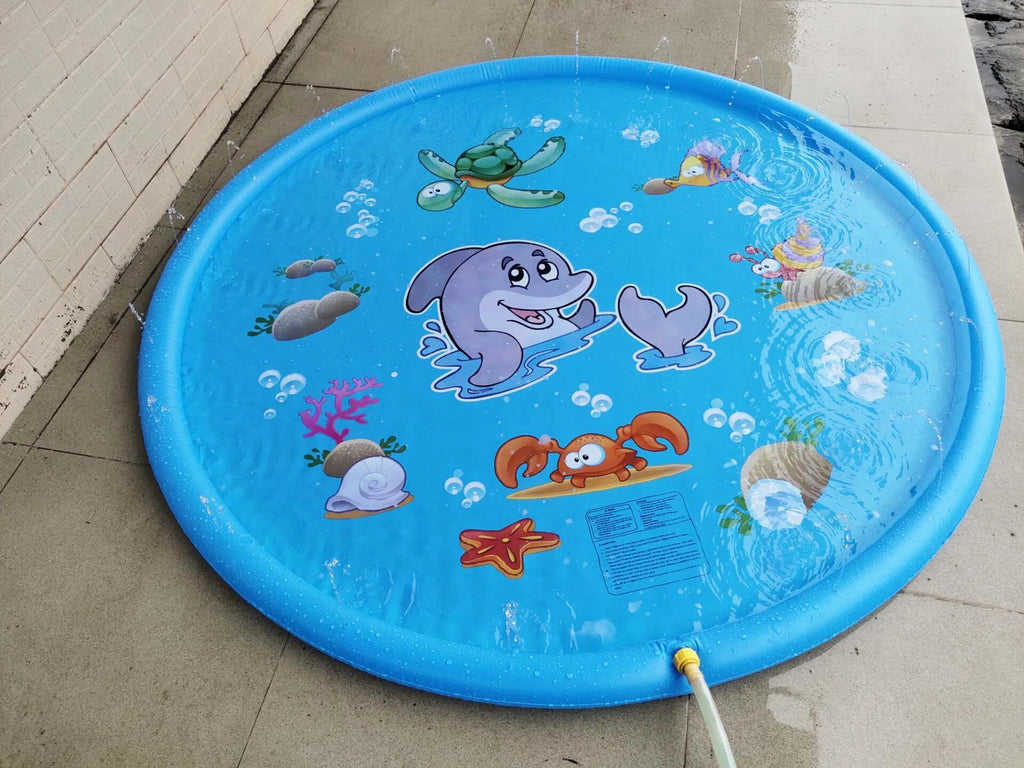 Blue children's water spray mat with marine animals laid on grass, connected to a garden hose.