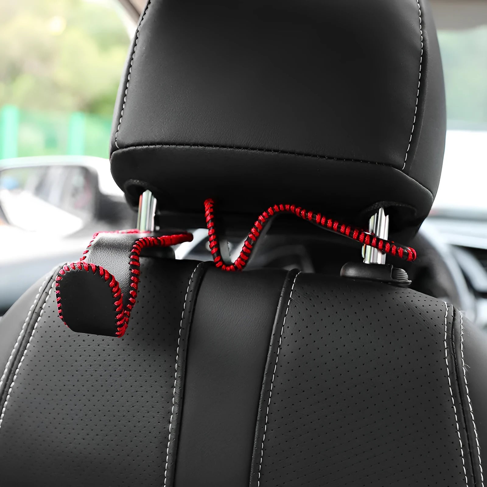 Stainless steel car seat back hook with gold finish clipped onto a car headrest, holding a shopping bag.