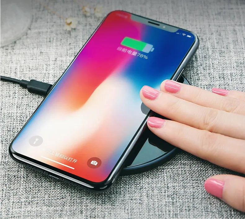 A black or white glass disc wireless charger on a table, showing its sleek design.