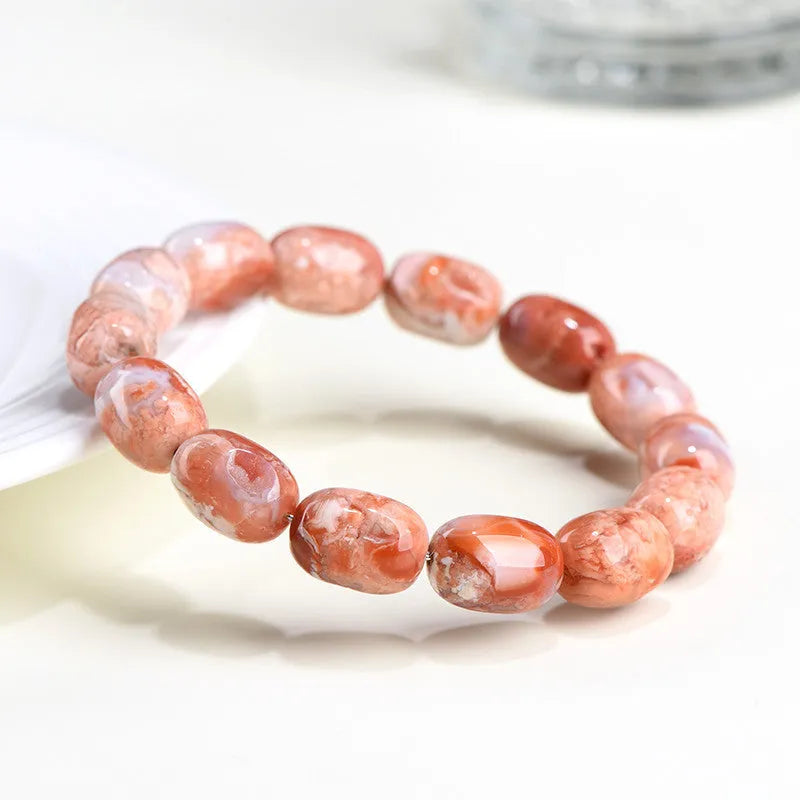 Natural cherry agate bracelet with geometric 10x14mm barrel beads and ruyi details on a wrist.