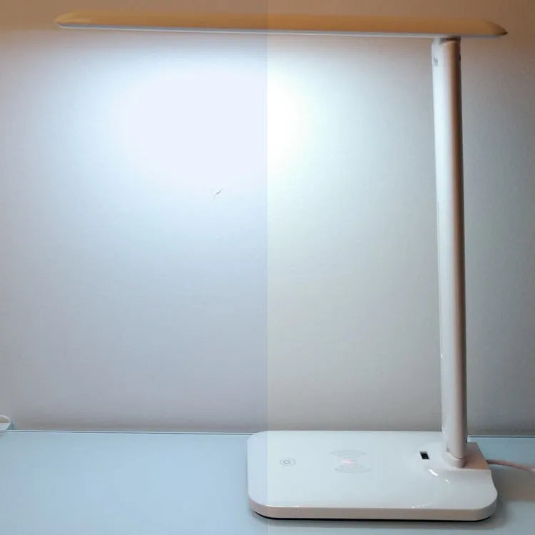 White eye protection desk lamp with wireless charging pad and touch dimmer on a desk