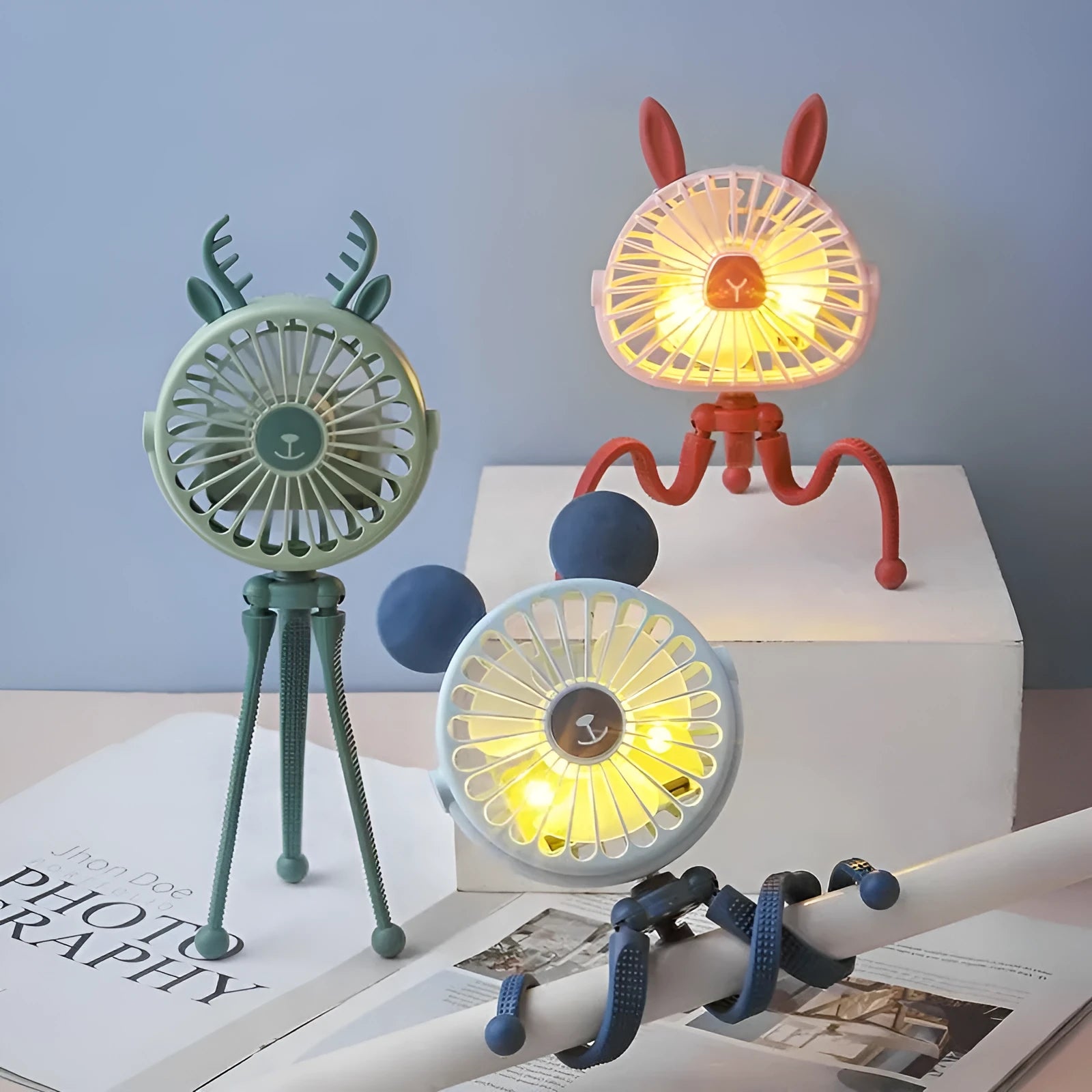 Pink portable USB rechargeable fan with animal design and clip attached to a stroller handle.