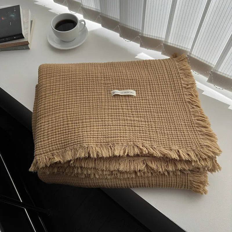 Four-layer gauze cotton blanket with tassel trim in avocado green, laid flat.
