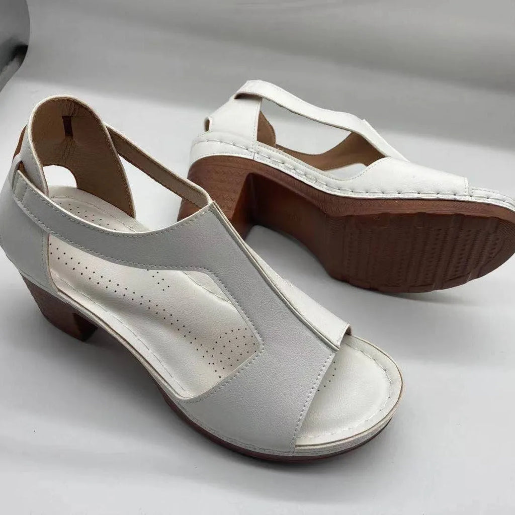 Women's beige peep toe wedge sandals with a buckle strap, shown on a foot.