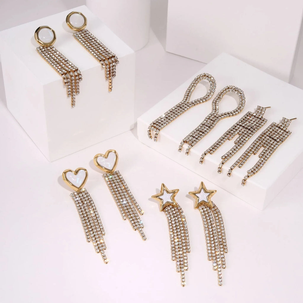 Close-up of a pair of gold plated stainless steel earrings featuring a heart shape design with diamond tassel and geometric star details.